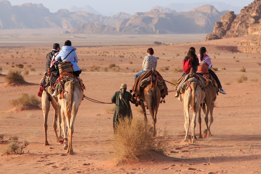 Wadi Rum, Jordan - March 24,2015: Tourists riding camels at sunset in the Wadi Rum desert, Jordan